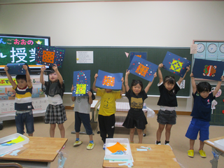 作品を高く掲げて見せるこどもたち