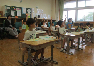 見つけたことを話そうと手を挙げるこどもたち